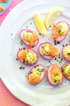 a white plate topped with deviled eggs and lemon wedges