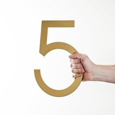 a hand holding the number five in front of a white background