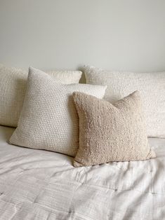 three pillows on top of a white bed