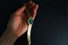 "Fine watch bracelet set with a jade donut and accented with diamonds in 18k. The donut is a deep green Omphacite jade, in parts dark and light like a globe lit. This jewel borrows the perfect finish of a Vacheron watch, its Omega straps in original burnished solid gold. More than a conversion piece, this bracelet could not have been refined to a sleeker layout. At 2cm, the donut is considered big yet its size is offset by the straps, and vice versa. The straps though wide feel made for its cent Luxury Green Round Jewelry, Timeless Green Jewelry For Evening, Timeless Green Evening Jewelry, Modern Green Jewelry For Formal Occasions, Elegant Green Watch As A Gift, Elegant Green Watch For Gift, Elegant Jewelry And Watches With Single Cut Diamonds, Luxury Oval Jewelry With Diamond Hour Markers, Formal Round Jade Jewelry