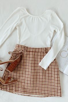 A plaid skirt outfit is an essential look for fall fashion. The colors of autumn come together in a checker pattern throughout the mini skirt. Style with a simple white bodysuit and ankle booties and grab a pumpkin spice latte on the way! #lovelulus Bodysuit And Skirt Outfit, Thanks Giving Outfits Women, Thanks Giving Outfits, Outfit For School, Checker Pattern, Thanks Giving, Women Skirt, Traje Casual