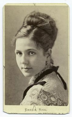 an old black and white photo of a young woman with her hair in a bun