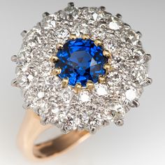 The ring is centered with one (1), prong set, round mixed cut natural sapphire set into a twelve-yellow gold prongs, and surrounded by 18K white gold double halo setting accented with twenty-eight (28), prong set, old European cut diamonds. The ring is finished with a reverse tapered 14K yellow gold shank. The ring measures 15.2mm at the top, rises 6.1mm above the finger, tapering to 2.1mm wide and 0.9mm thick at the base of the shank. This ring is currently a size 5 and we offer complimentary r Dazzling Yellow Gold Sapphire Ring With Brilliant Cut, Dazzling Yellow Gold Sapphire Ring, Sapphire Cluster Ring With 17 Jewels, Fine Jewelry Sapphire Ring With Rose Cut Diamonds, Blue Round Sapphire Ring With Rose Cut Diamonds, Sapphire Ring In Yellow Gold With Halo Setting, Fine Jewelry Yellow Gold Sapphire Ring With Halo Setting, Sapphire Ring With Rose Cut Diamonds, Yellow Gold Sapphire Ring With Halo Setting