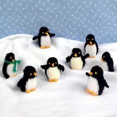 small knitted penguins sitting on top of a white blanket