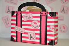 a pink and black striped bag with stickers on the handles is sitting on a table