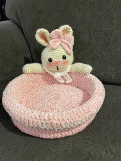 a crocheted stuffed animal sitting on top of a pink bed in the shape of a ball