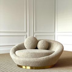 a round chair with two balls on it in front of a white wall and beige carpet