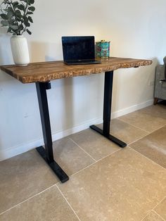 a laptop computer sitting on top of a wooden table next to a potted plant