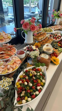 a buffet table filled with lots of different types of food and flowers in vases