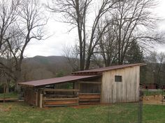 a small barn with a metal roof in the middle of a field