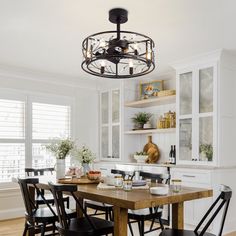 a dining room table with black chairs and a light fixture hanging over it's head