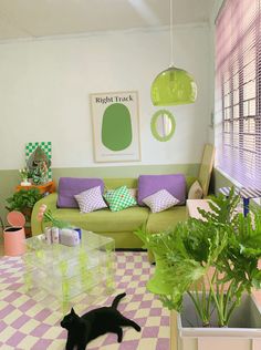 a black cat laying on top of a checkered floor next to a green couch