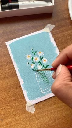 a person is drawing daisies on a piece of paper