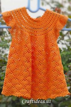 an orange crocheted top hanging on a clothes line