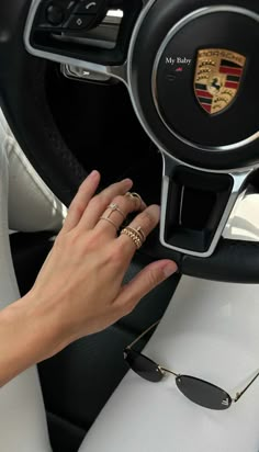 a woman's hand on the steering wheel of a car with her gold ring