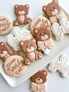 cookies decorated with teddy bears and words on a white platter next to other cookies