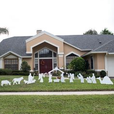 a house with lawn decorations in front of it and several cats on the lawn outside