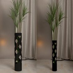 three tall black vases with plants in them