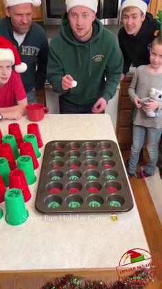 a group of people standing around a pan filled with cupcakes and christmas decorations