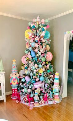 a brightly colored christmas tree in the corner of a room with toys and decorations on it