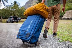 a man pulling a blue suitcase down the road