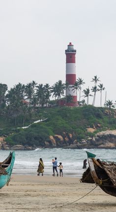 two boats sitting on top of a beach next to the ocean near a light house