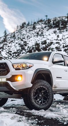 a white truck parked on top of snow covered ground