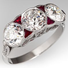 three stone diamond ring with red stones on the sides and white diamonds in the middle