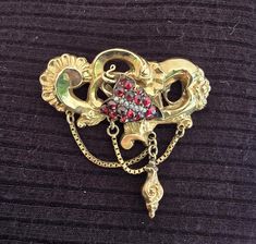 This antique pin, from the Biedermeier Era (1815-1848), is absolutely gorgeous.  It is solid gold and is in excellent condition.  The gold is a very rich, buttery color and boasts a beautifully intricate design of swirls with a tiny carved flower, two swinging drop chains with a dangling pendant, a cluster of grapes, made with dark red garnets and seed pearls.  A stunning piece that has garnished many compliments.   It is an early piece, pre-dating any markings but has been tested/confirmed by a Traditional Yellow Gold Brooches For Formal Occasions, Traditional Yellow Gold Formal Brooches, Antique Yellow Gold Brooches With Intricate Design, Yellow Gold Baroque Brooch For Formal Occasions, Formal Yellow Gold Baroque Brooches, Vintage Yellow Gold Baroque Brooch, Antique Hallmarked Yellow Gold Brooches, Antique Yellow Gold Filigree Brooches, Antique Yellow Gold Hallmarked Brooches