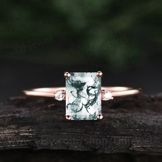 an engagement ring with a green and white marble in the center on top of a piece of wood