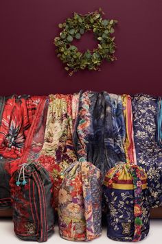 a bunch of bags sitting on top of a white counter next to a wreath and purple wall