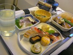 an airplane meal on a tray with a glass of water and two bowls of food