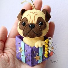 a hand holding a small stuffed pug dog in a purple and blue box with stars on it