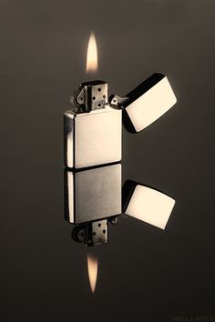 a lighter is lit up in the air with its reflection on the surface and it appears to be melting