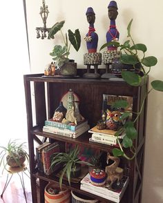 a shelf filled with lots of potted plants and figurines on top of it