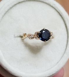 a ring with a blue stone in it sitting on a white velvet display case,