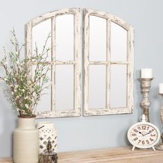 an old window frame is next to a vase with flowers and candles on a mantle