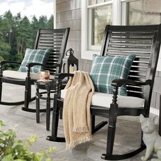 two rocking chairs sitting on a porch next to a cat