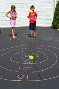 two children standing in front of a chalk drawing on the ground