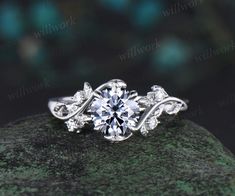 a white gold engagement ring with an intricate vine design on the band and center stone