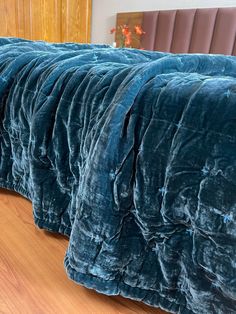 a row of blue velvet bedspreads sitting on top of a hard wood floor