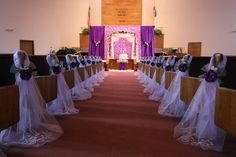 the aisle is lined with veils and purple sashes, along with flower arrangements