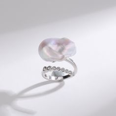 Cessie Ring: Dive into elegance with our Cessie ring, showcasing a striking large baroque freshwater pearl nestled at its heart. Its unique allure is amplified by a gracefully curved arrangement of glistening cubic zirconia, adding just the right touch of sparkle. This masterpiece offers both delicacy and a statement, embodying the perfect balance for modern sophistication Material: 925 Sterling Silver, extra large bold pearl, and cubic zirconia Flexible size with open closure Note: Our jewelry Elegant Baroque Pearl Drop Ring, Elegant Baroque Pearl Open Ring, Baroque Pearl Ring For Anniversary, Elegant Baroque Pearl Ring As A Gift, Elegant Baroque Pearl Ring For Gift, Elegant Baroque Pearl Ring For Wedding, Elegant Baroque Pearl Wedding Ring, Elegant Silver Baroque Pearl Rings, Elegant Silver Rings With Baroque Pearl