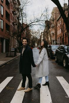 a man and woman holding hands while crossing the street