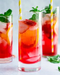 three glasses filled with different types of drinks and garnished with mint, lemon, and strawberries