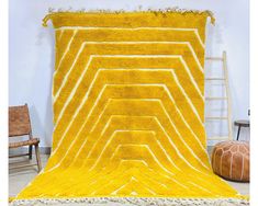 a yellow rug with white lines on it and a chair next to it in front of a wall