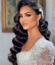 a woman with long dark hair wearing a wedding dress and tiara is looking at the camera