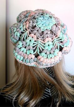 the back of a woman's head wearing a crocheted hat with flowers on it