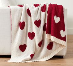 a red and white blanket with hearts on it is sitting on the floor next to a couch