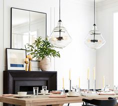 a dining room table with chairs, plates and candles in front of a mirror on the wall